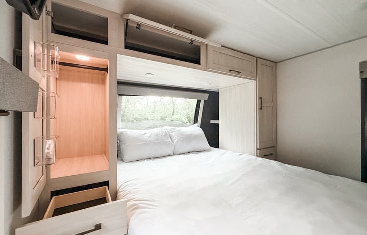 Primary bedroom with hanging closet, overhead storage, drawers, under-bed storage, and bedside shelves.