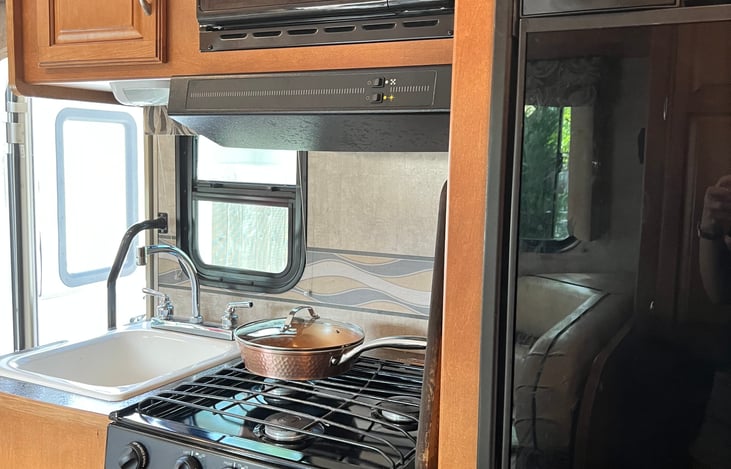 Two-piece refrigerator and freezer. Oven, three-burner stove, sink. The kitchen comes equipped with copper pots and pans, kitchen utensils, large wooden cutting board, flatware, cups, plates, and more