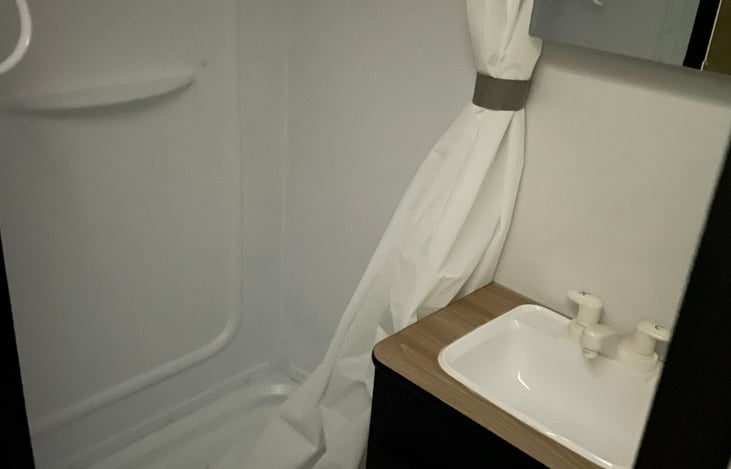 Bathroom has a shower, a vent, a sink and toilet.  All the essentials!