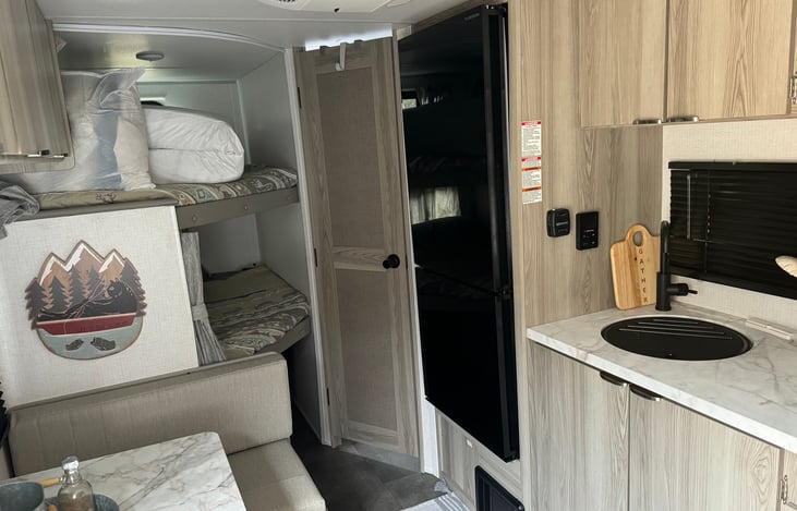 Full size fridge and get this the door can open from either side! "Just not at the same time"
Note the bunkbeds have privacy curtains. 
The door next to fridge leads to the bathroom