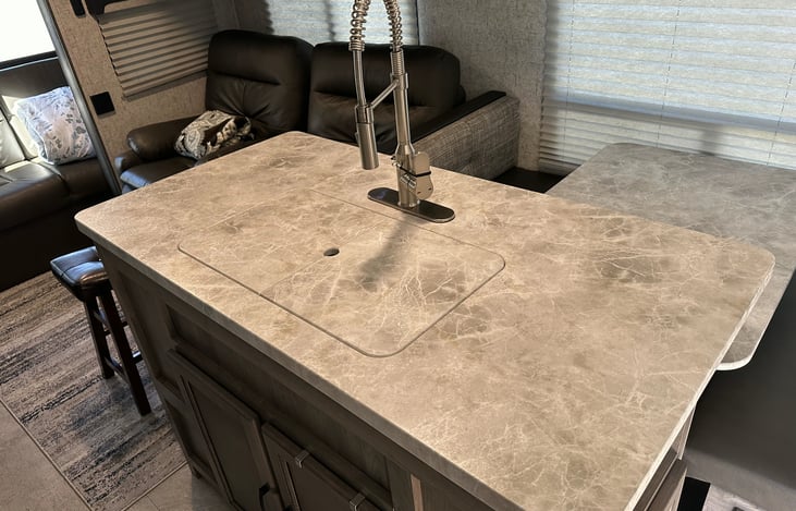 Center island in kitchen with home-style faucet and spray head. Sink covers provide extra counter space as needed.