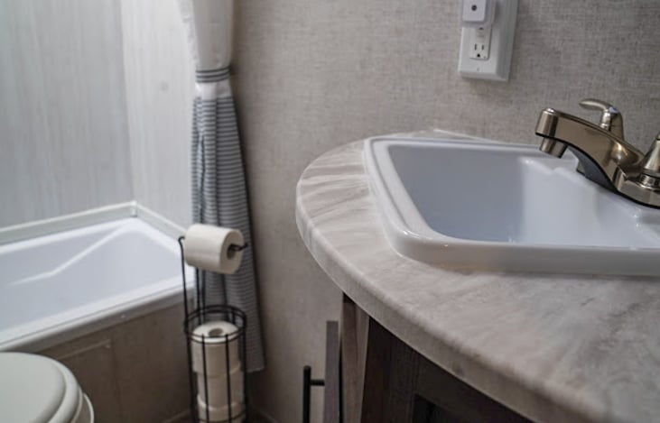 Corner vanity offers extra counter space, storage below, and a mirrored medicine cabinet with plenty of additional storage.