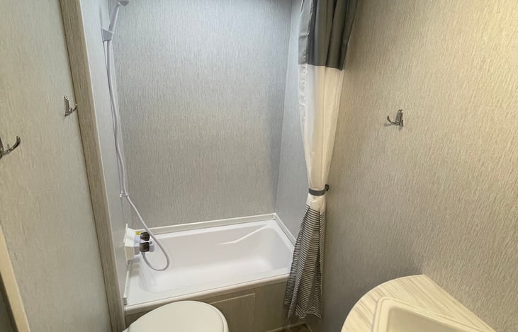 This is the one restroom in the RV that has a shower with a mini bath, toilet, and sink.