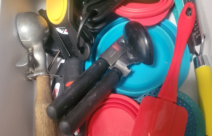 Utensil drawer in kitchen- measuring cups, can opener, small cheese grater, ice cream scoop, can strainer