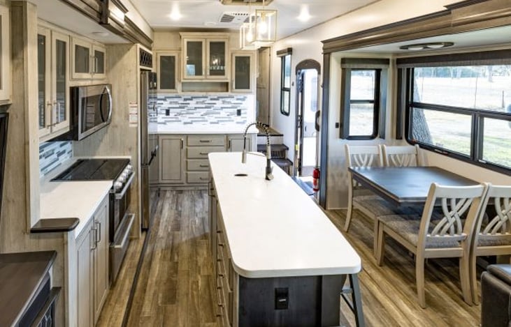 Kitchen area includes full size refrigerator, microwave, 4 burner stove top and oven, island  with sink and seating for 3 on island/stools and 4 seat dinning area