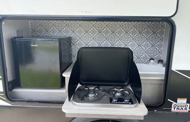 Outside kitchen complete with 2 burner gas cook top, fridge, and sink.