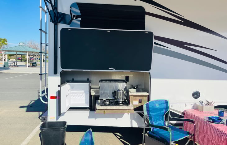 exterior mini fridge, 2 gas burners, sink with water.