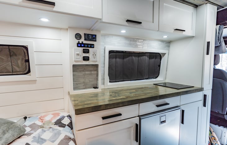 This kitchen galley is complete with a built in induction cooktop, 130L fridge, so much storage, and is home to the battery monitoring system!