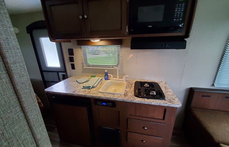 kitchen area - electric/propane fridge, two burner stove and vent hood, sink, and microwave