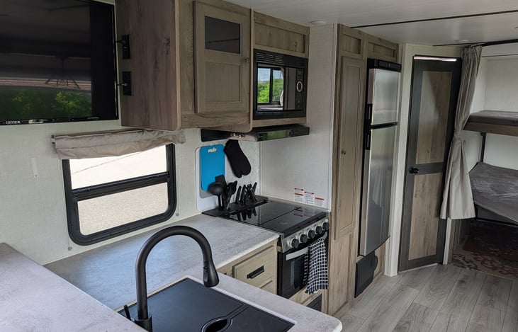 Kitchen featuring fridge/freezer, stove top, oven, sink and storage.