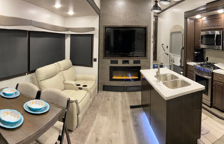 Living room / dining area with large flat screen Firetv, BT stereo system, fireplace and dual reclining sofa.