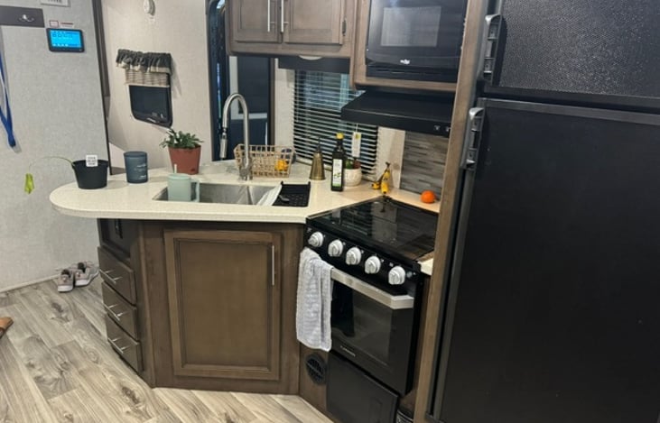 Kitchen area with stove, microwave, and refrigerator