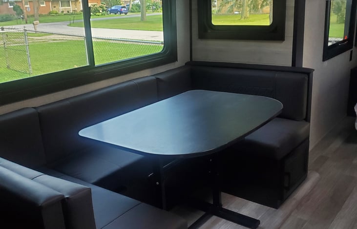 Dinette table folds down for another bed for guests. Table must be folded down and secure when transporting camper.  Extra linens in cabinet under dinette.
