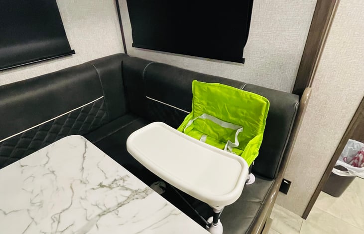 Collapsible toddler seat that can strap or sit almost anywhere is provided in drawer below dinette.