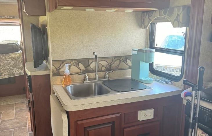 Kitchen area has sink, microwave, stove, and refridgerator.