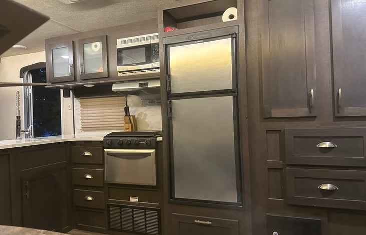 Kitchen area with prep counter, stove, fridge & microwave