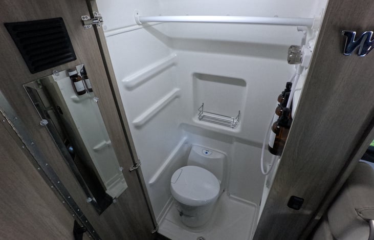 Wet bath includes shower faucet, shampoo/body wash/conditioner, toilet paper box, extra storage, mirror and a cassette toilet.