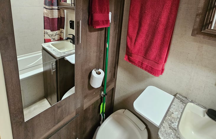 Bathroom features mirrored closet door, cleaning supplies, toilet paper holder and starter rolls, and soaking tub.