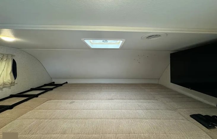 Overhead bunk bed with privacy curtain and TV that on swivel arm that swings out to living area too.