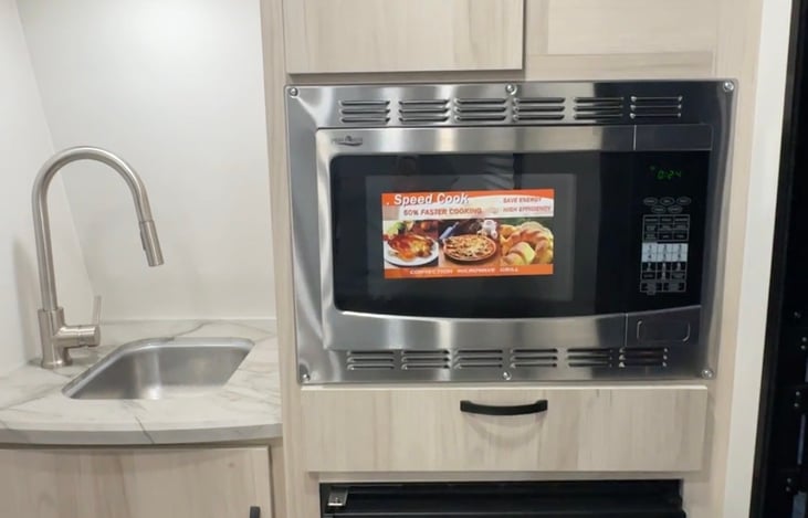 Kitchenette includes sink, space for storage above and below the sink, microwave that doubles as an oven,  storage for cooking supplies above that and a small super cold fridge below.