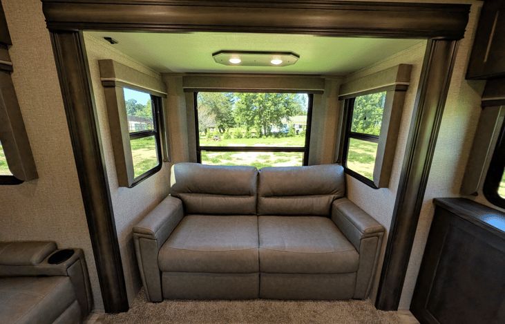 Gourmet galley & rear den retreat! Includes a 12 cu ft fridge, pantry, stove/oven, dual sofas, theater seats, 50" TV, electric fireplace, and 3 slides for spacious high-end living.