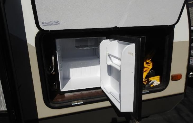 Next to this outdoor fridge is plenty of extras, marshmallow skewers, outdoor grill, camp mat, outdoor door mat, camp chef gas grill, charcoal chimney, etc