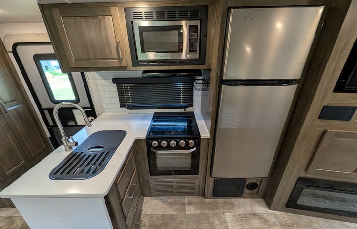 Spacious open-concept living area w/ dual recliners, TV & fireplace. Full kitchen features a residential fridge, 3-burner stove, oven, microwave, deep sink & booth dinette! Natural light throughout.