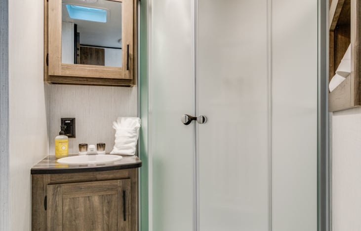 Full bathroom with shower, sink, toilet and storage for toiletries.