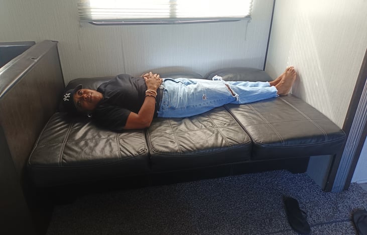 Sofa bed in bed position highlighting that  2 small adults or 2 children can sleep here. She's she's 4'11¾" 😂