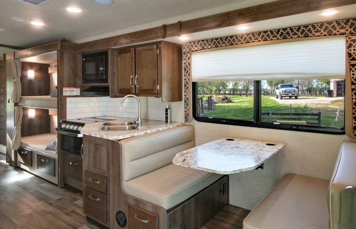 This picture shows the gas stove, microwave, twin bunk beds, and dining table which can also be converted into a sleeping quarter.