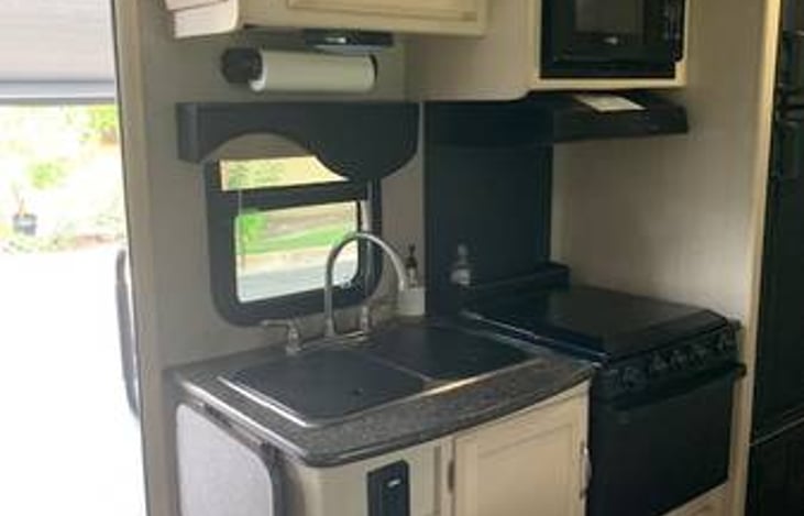 Very clean kitchen area has twin sinks, 4 burner stove and oven, overhead exhaust fan with light, 3 drawers, under and above sink storage area, and microwave oven. Pots/pans/dishes/utensils included.