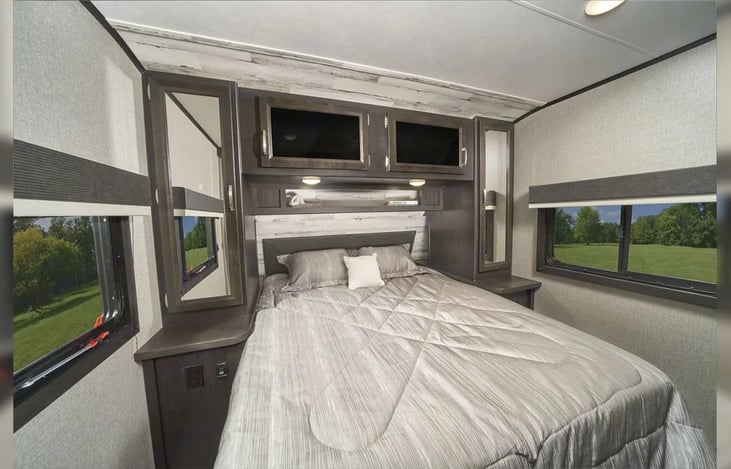 Master Queen bed with lights on headrest and storage beside, under and above for personal items. Chargers ready on side tables. Privacy pocket door closes off master.
