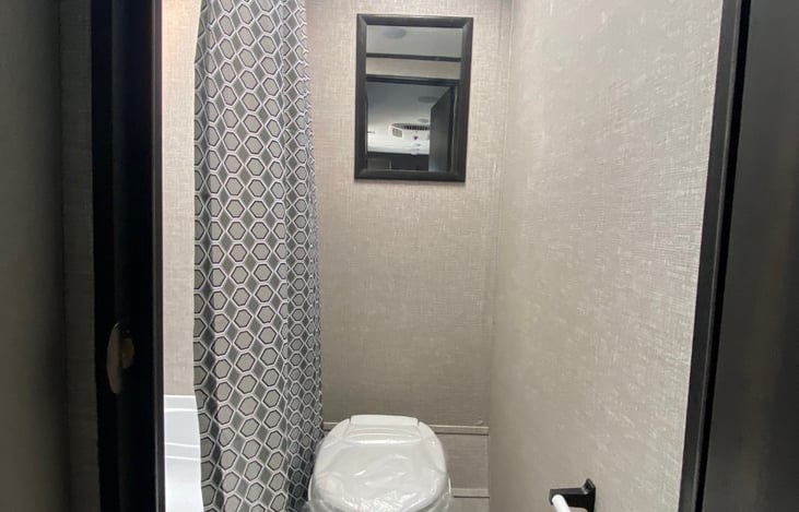 Necessity room with toilet and shower including small tub.