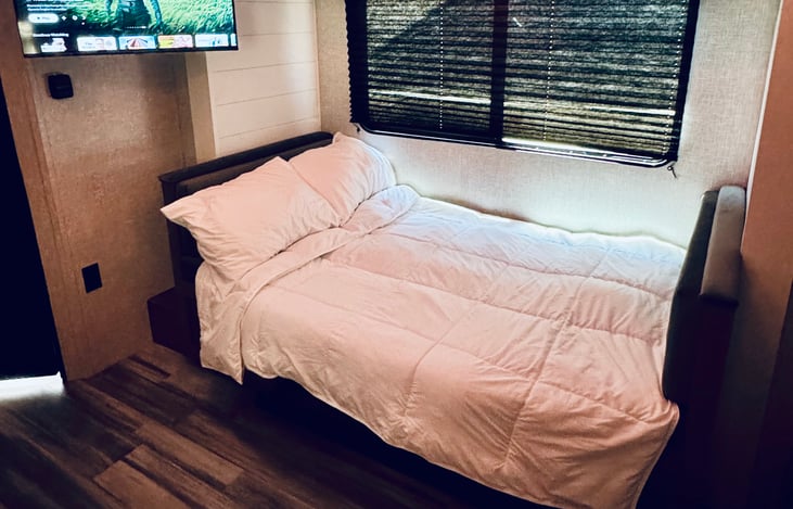 The U-shaped design transitions nicely from a social seating area into a full bed. The white flannel sheets make the converted space look clean and comfortable for an overnight stay.