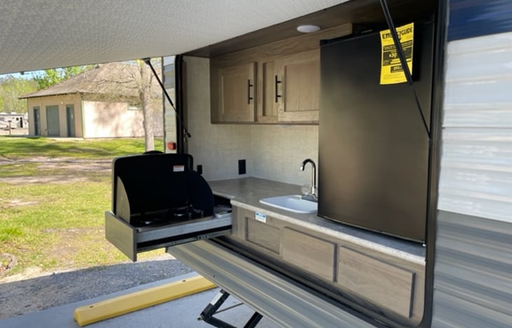 Outdoor kitchen area with two burner cook top, refrigerator and sink. Lots of storage for snacks also!