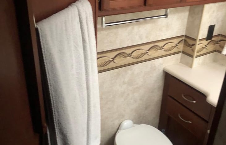 Spacious bathroom with shower, sink, toilet and extra cabinets for storage.