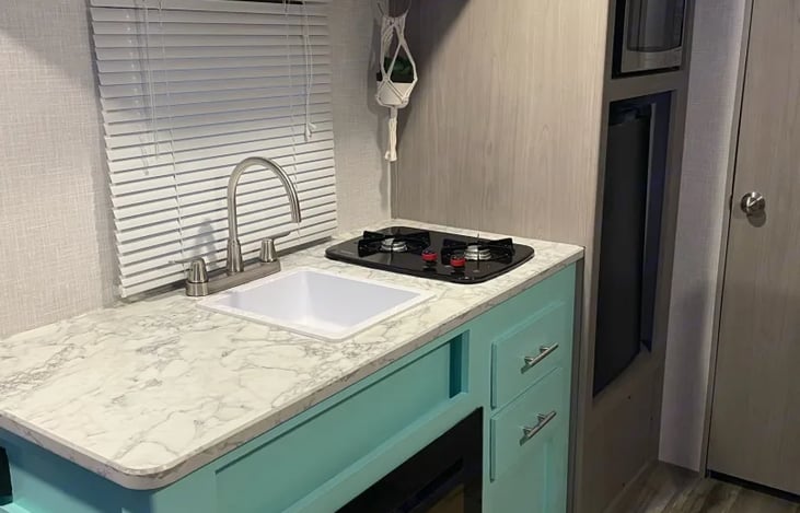There is a microwave, a two burner stove top, and a fridge. Under the sink is a little electric fireplace which is how the camper is heated. It's very cute and aesthetically pleasing.