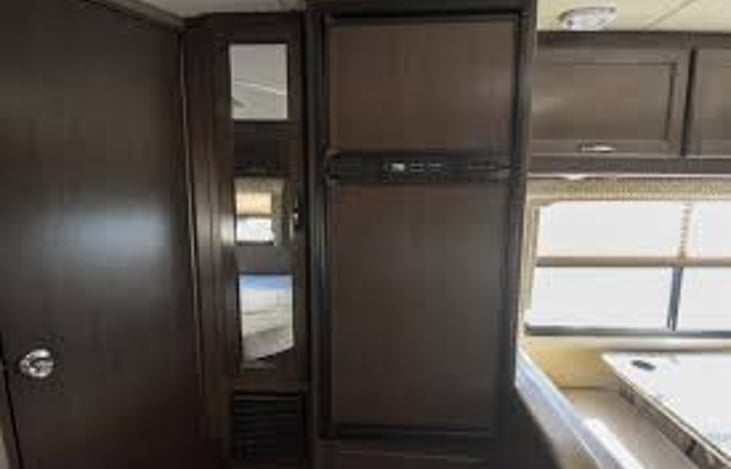 Refrigerator & wardrobe closet with a mirror on the door.