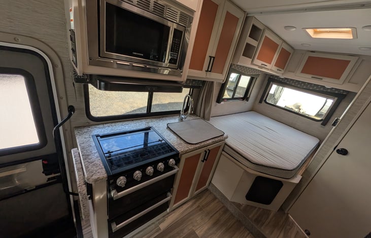 Bright, modern interior with a cute pop of color! Features a cozy rear queen bed, fully equipped kitchen, converting dinette, over-cab bunk, and an accent armchair. Clean, open, and ready for adventur