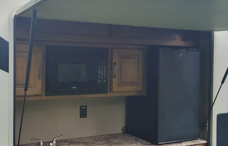 outdoor kitchen with a 2 burner stove, mocrowave, small fridge and sink