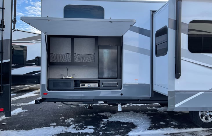 Outdoor Kitchen with sink, griddle and fridge.