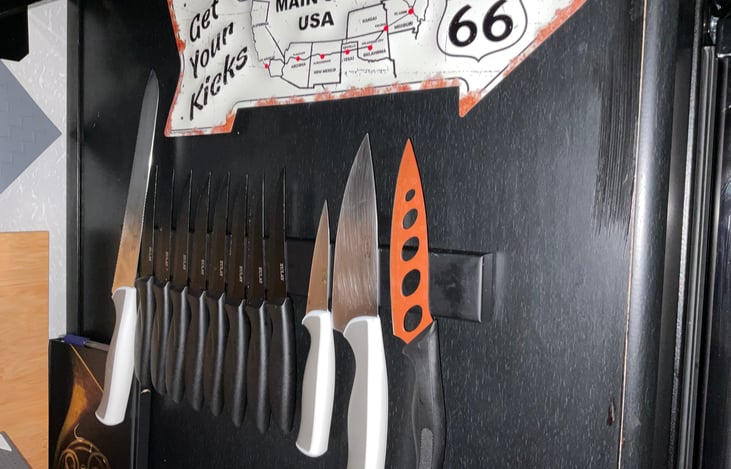 Knife rack with steak knifes and chef’s kitchen knives. The cutting board stays in place with magnets conveniently located behind the stove.