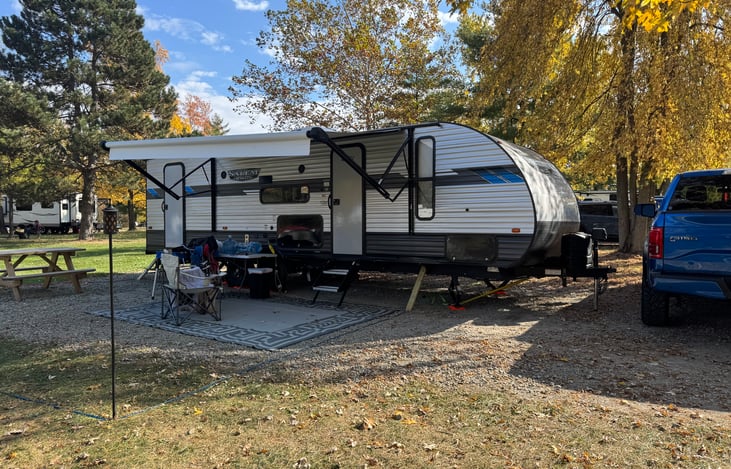 Outdoor set up with awning out. Also comes with an outdoor rug and 4 folding chairs.