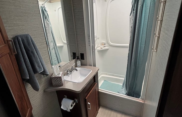 Bathroom with sink, shower, storage cabinet and toilet.