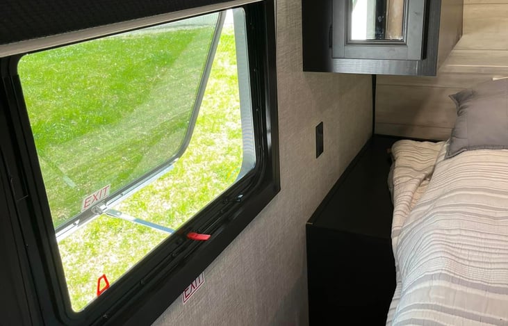 Main bedroom with narrow cabinet to the side, wall plugs, window, over-bed and under-bed storage.