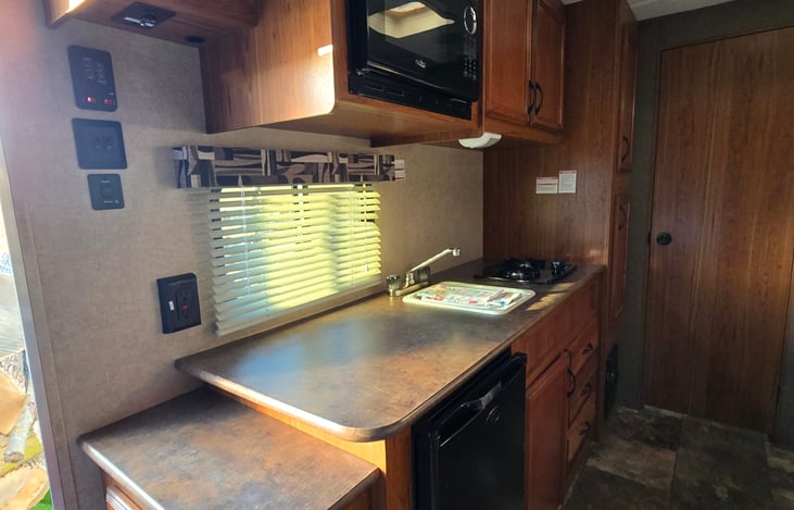 Kitchen features microwave, 2 burner stove, mini fridge, sink & radio