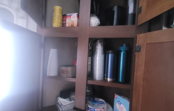 fully stocked pantry with cups and coffee supplies including a coffee maker