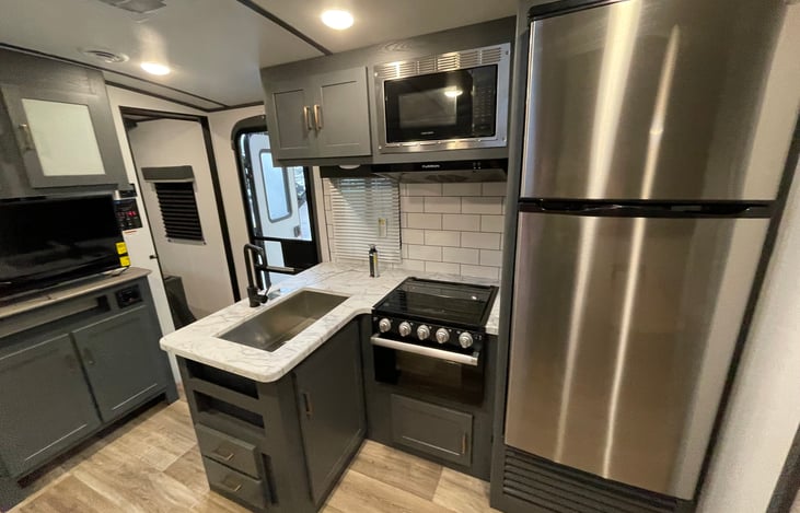 Large Fridge and Freezer with Ice Trays. 3 Burner Propane Stove Top with oven. Includes cookware, utensils, dishes, Keurig Coffee Pot, paper plates, plastic cups, all necessities to cook and eat!