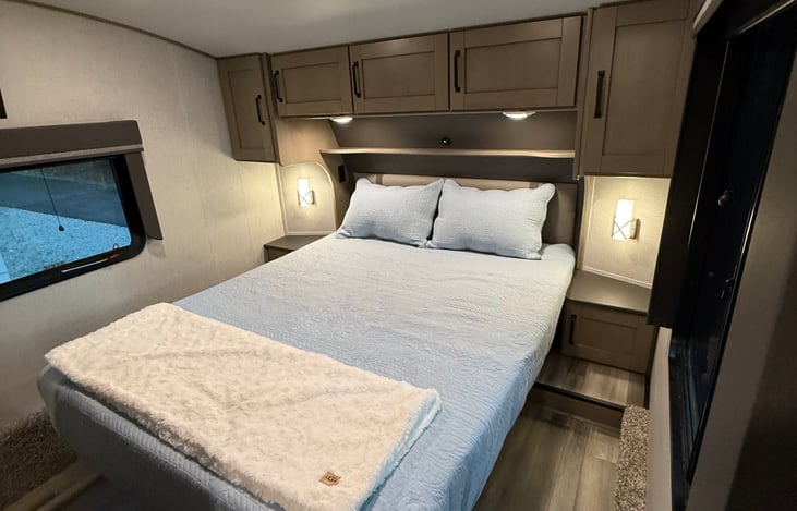 Queen bed with various light fixtures. Storage beneath bed as well as a closet and cabinets.