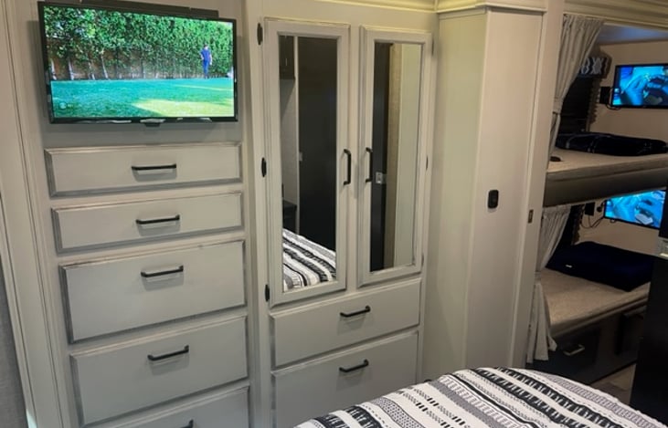 Master bedroom with TV, drawers, and closet.